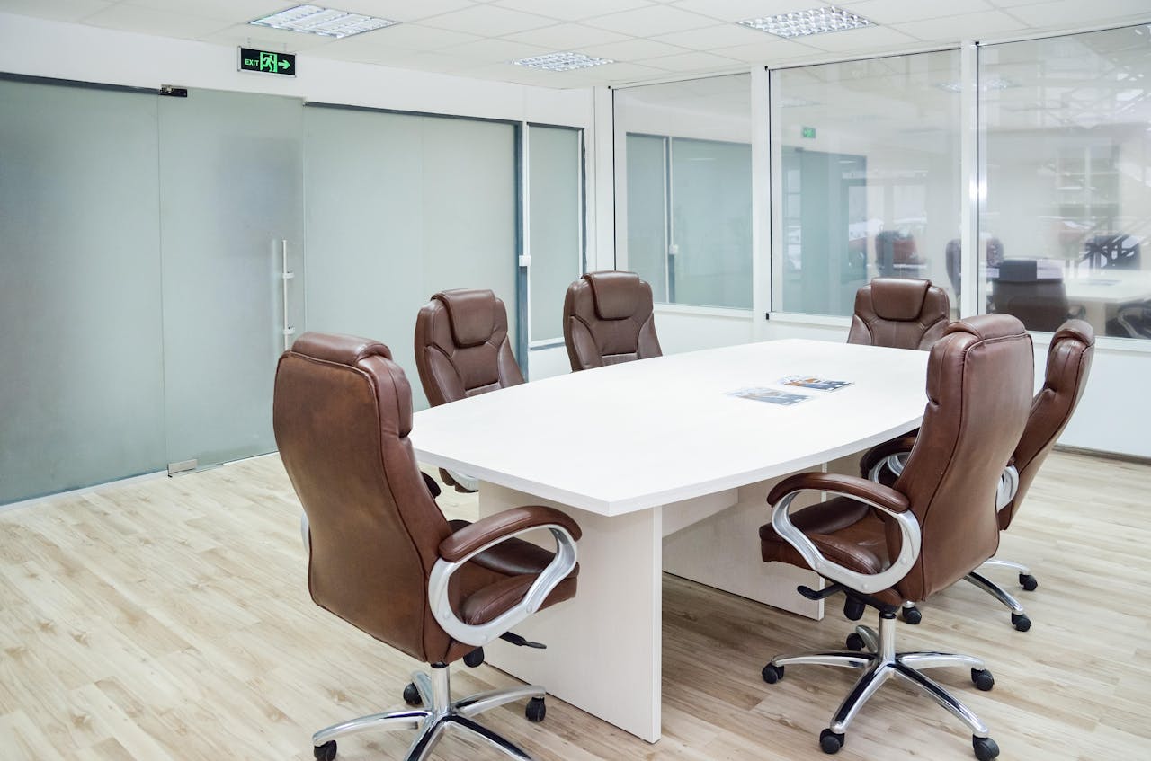 Spacious conference room with modern design, featuring leather chairs and a white table.