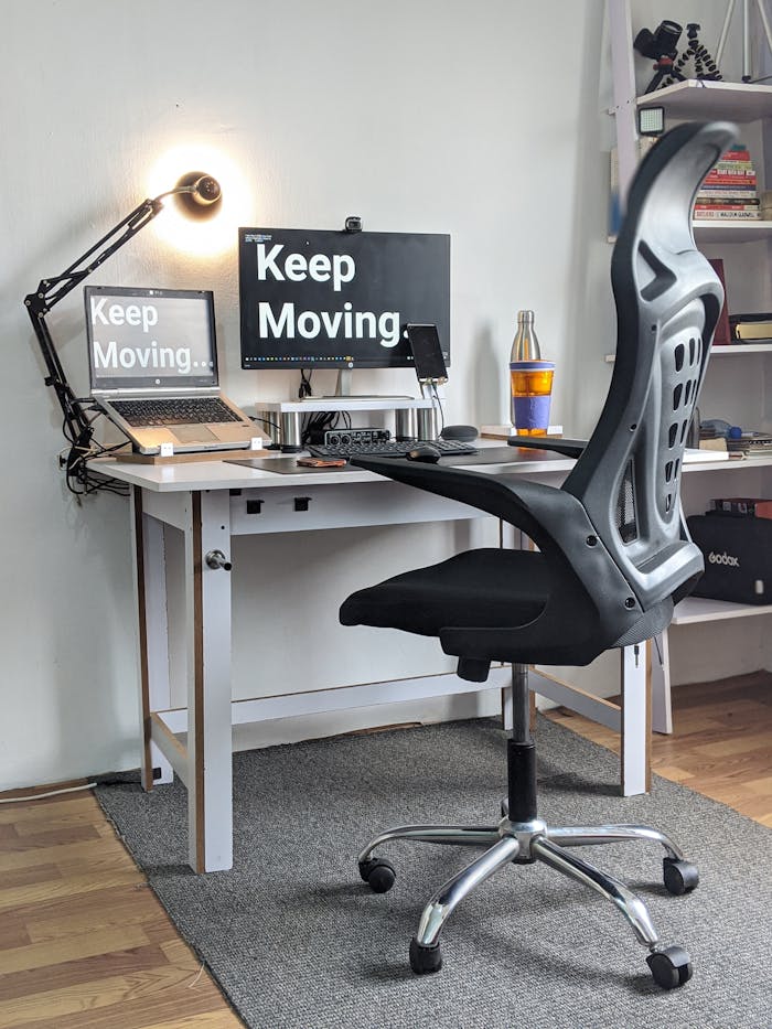 Stylish home office with ergonomic chair, desk, laptop, and motivational screens.
